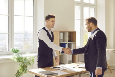 İş adamları iş yerinde masanın üzerinde el sıkışıyor toplantıyı bitiriyor, başarıyı veya başarıyı kutluyor, iyi bir anlaşma yapıyor, kontrat imzalıyor veya yeni bir çalışanı selamlıyor..