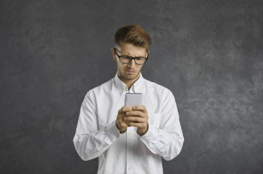 Man having problem with mobile app and looking at phone screen with unsatisfied discontent confused face expression. Young guy gets negative money balance notification on his modern cellphone