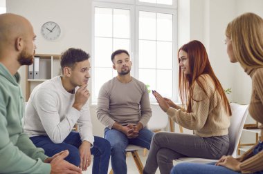 People in group therapy having a discussion. Several men and women having a psychotherapy session together, sitting in a circle, talking about their problems, and trying to suggest possible solutions