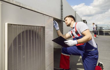 Çatıdaki havalandırma, havalandırma, havalandırma ya da havalandırma sistemini tamir eden işçi ya da mühendis. Bakım işi, bina iklim kontrol ekipmanlarının çalışmasını güvence altına alır.