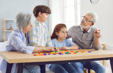 Torunlar ve büyük ebeveynler evde birlikte oynayarak ve mektup öğrenerek mutlu zaman geçirirler. Eğitimsel aile aktivitesi, öğrenme sürecinde neşeyi teşvik eder ve bağları güçlendirir.