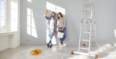 Çift yeni evlerinde oda dekorunu tartışıyor. Evlerinde boya rulosu yenileme ve dekorasyon odası olan mutlu eşler. Ev taşıma, yenileme.