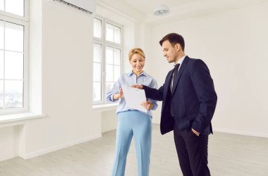 Pozitif kadın emlakçı ya da emlakçı bir müşteriye yeni bir ev ya da ofis gösteriyor. Acente uzmanlığı ve adanmışlığı sorunsuz ve başarılı bir emlak satın alma deneyimi sağlar.