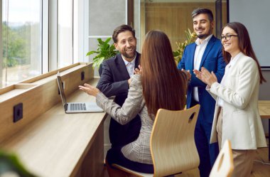 Bir grup mutlu iş adamı işyerinin yakınında duruyor ve başarılı bir anlaşma yapıyorlar ya da sözleşme imzalıyorlar ya da yeni çalışanları selamlıyorlar. İş arkadaşları iş arkadaşlarıyla konuşup alkışlıyorlar..
