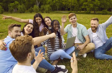 Mutlu, neşeli, çoklu etnik çeşitlilikte öğrenciler ve arkadaşlar parkta yeşil çimlerde oturuyor, grup projesinde birlikte çalışıyorlar, dizüstü bilgisayar kullanıyorlar, eğleniyorlar, gülüyorlar ve sadece pozitif duyguları paylaşıyorlar.