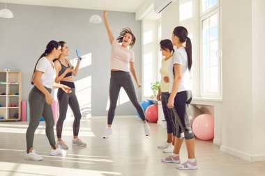 Spor salonunda başarılı bir spor yaptıktan sonra eğlenen mutlu bayan sporcu. Enerji dolu genç bir kadın spor rekorunu kırıyor, arkadaşlarıyla kutluyor ve heyecanla zıplıyor.