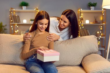 Anne ve küçük kızı hediye kutusuyla, aşık bir aile, mutlu annelik duyguları. Ebeveynler ve gençler bayram hediyelerini kutluyor, birlikte iyi vakit geçiriyorlar, sağlıklı ilişkiler kuruyorlar.