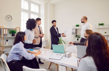 Genç kendine güvenen bir iş adamı şirket büyümesi ve finansman hakkında konuşuyor toplantıda iş projesini tartışıyor. Çalışma konferansında iş arkadaşlarıyla modern ofiste oturan insanlar. Takım çalışması konsepti