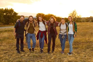 Bir grup turist doğa turu sırasında sırt çantalarıyla yürüyüş yapıyor. Yürüyüş gezisindeki kadın ve erkekler bir sırada kameraya bakıyorlar. Seyahat ve turizm kavramı.