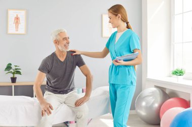 Genç hemşire, hastanede buluşmada gülümseyen olgun bir hastanın omzunu tutan, üniforma giyen, üst düzey bir adamı rahatlatan ve destekleyen, tedavi eden, empati ve iyi bakım gösteren bir doktor. 