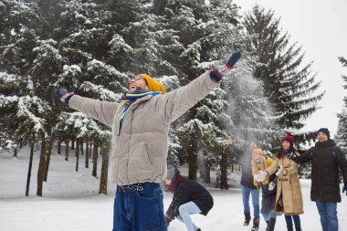 Kışın karla kaplı ormanda yürüyen bir grup genç arkadaş kartopu oynarken eğleniyor. Adamın portresi, kollarını arka planda uzatmış arkadaşlarının ona kar fırlatırken..