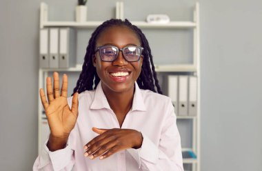 Mutlu gülümseyen Afro-Amerikan kadın el sallayarak merhaba diyor. İnternette web sitesi, video görüşmesi ya da iş arkadaşı ya da bir arkadaşıyla görüntülü görüşme yapıyor. İnternet iletişimi kavramı.