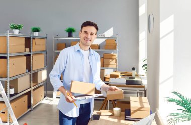 Depoda ya da postanede çalışan mutlu bir işadamının portresi. Paketlerin envanterini yapıyor. Ambalajı yönetirken yaptığı işten duyduğu memnuniyeti yansıtıyor. .