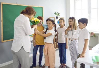 İlkokulda öğretmenlerine çiçek veren çocuklar tatilde onu kutluyorlar. Onlar sınıfta gülümsüyor ve ona bakıyorlar. İyi tavır, özen ve saygı kavramı.