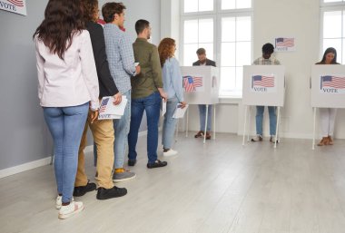 ABD vatandaşları oy kullanma hakkını kullanmak için sıraya girdiler. Seçim günü coşkusu, seçmenlerin Amerikan bayraklarıyla süslenmiş oy verme kabinlerine girmek için sıralarını bekledikleri seçim merkezinde hissediliyor..