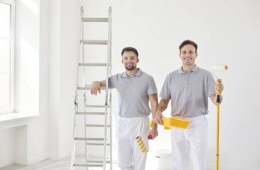 İki mutlu adamın portresi, ressamlar, evde, apartmanda ya da inşaatta. Takım çalışması ve memnuniyet, projeye katkıyı vurgulamak ve çalışmada buldukları neşe.