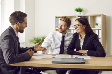 Üç iş arkadaşı ve çalışanlardan oluşan bir grup bir şeyi tartışıyor, anlaşmaya varıyor ve kontrat imzalıyor. Şirket çalışanları ofiste toplantı yapıyor ve gülümsüyor..