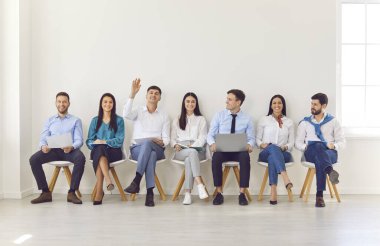 Ofisteki bir iş toplantısında bir grup iş arkadaşı soru sormak için el kaldırıyor. Halkın takım çalışması sunum, grup çalışması ve çalışmaya olan bağlılığı.