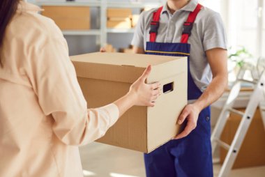 Teslimat servisinden bir adamın elinde karton kutuyla kadının olduğu resmi kapat. Lojistik veya dağıtım merkezinde çalışan insanlar müşteri için sipariş hazırlıyorlar. Stok envanteri.