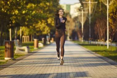 Kadın koşucu parkta egzersiz yapıyor. Sağlıklı yaşam tarzını ön plana çıkarıyor. Her adımda canlılık ve refah koşucusunun doğada koşması için kardiyo çalışmalarının ruhunu somutlaştırıyor.