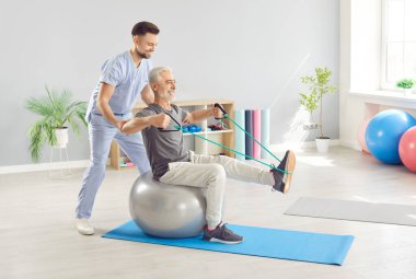 Yaşlı bir hastanın rehabilitasyonuna katılan, fizik tedavi egzersizleri yapan bir doktor ya da hemşire. Yaşlılar için spor ve sağlığın alıştırma yoluyla desteklenmesinde tıbbi profesyoneller.