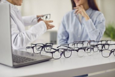 Doktor göz doktoru, gözlük reçetesi için bir hastaya danışmanlık yapıyor. Göz bakımı ve sağlık hizmetlerine odaklanarak, hastanın en iyi görüş için doğru reçeteyi almasını sağlamak.