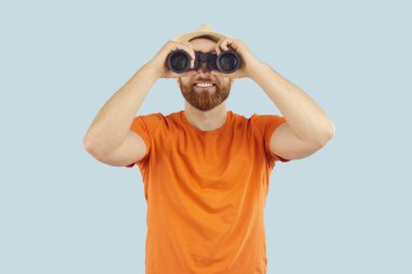 Dürbünle bakan mutlu bir adam. Yaz tatili rüyasını dikkatle gözlemlemek için dürbün. Erkek turist boş zaman, eğlence, seyahat, dinlenmek, görmek ya da fark etmek için bekliyor. 