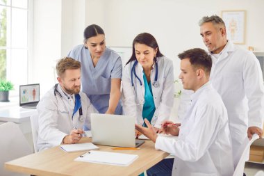 Doktorlar ve hemşireler bir toplantıya ya da hastanede konferansa katılacaklar. Grup çalışması, takım çalışmasını geliştirmek ve profesyonel ortamda işbirliği yapmak için bir dizüstü bilgisayar kullanmak..