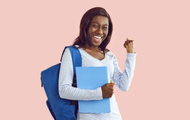 Not defteri ve sırt çantasıyla siyahi bir üniversite öğrencisinin portresi başarı ya da zaferi kutlamak için 