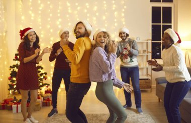 Mutlu çok ırklı gençler Noel 'i ev partisinde birlikte kutluyor. Gülümseyen uluslararası arkadaşlar dansı Yeni Yıl kutlamalarının keyfini çıkarın. Kış tatili kavramı.