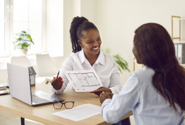 Yeni ev planlarını gösteren Afrikalı Amerikalı kadınlar, inşa, satın alma ve satma maliyetlerini tartışıyorlar. Mutlu tasarımcı profesyonel, mimar ofis danışmanlığı. Emlak ajansı, iş arkadaşları.