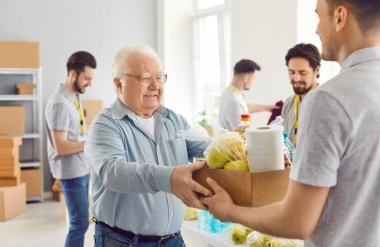 Zavallı yaşlı adam yemek yardımı alıyor. Hassas sosyal gruba mensup yaşlı bir vatandaş yardım kuruluşundan yardım alıyor. Minnettar yaşlı adam toplum merkezindeki market kutusunu alıyor. Bağış konsepti