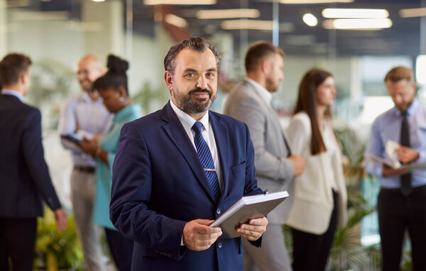 Зрелый серьезный бизнесмен, руководитель взрослой команды, наставник среди различных деловых людей в офисе, профессиональная встреча корпоративная портретная поза, исполнительный менеджер, владелец компании или руководитель проекта