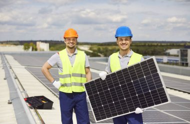 Çatıya güneş panelleri kuran mutlu bir elektrikçinin portresi. Fotovoltaik sistem üzerinde yapılan çalışmalar yenilenebilir enerji çözümleri ve profesyonel uzmanlığa adanmışlığı vurguluyor.