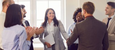 Ofis toplantısı sırasında iş arkadaşları el sıkışıyor. Etrafı iş adamlarıyla çevrili. Anlaşmada çalışma grupları arasındaki takım çalışması, işbirliği ve profesyonel birlik sergileniyor.