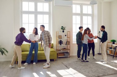 Çeşitli mutlu erkek ve kadınlar, arkadaşlar ve öğrenciler oturma odasında ev partisinde konuşuyorlar. Havayı hareketli sohbetler dolduruyor, enerjik takım arkadaşlıktan hoşlanıyor.