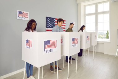 Bir grup mutlu Amerikan vatandaşının portresi. Seçim günü oy verme kabininde oy veren kadın ve erkekler oy kullanma merkezinde duruyor..