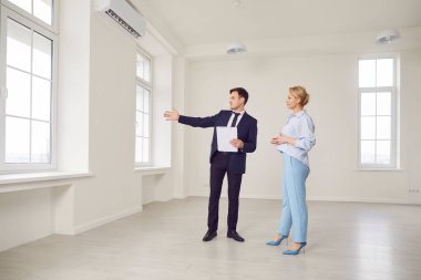 İş adamı ya da emlakçı müşteriye satın almak ya da kiralamak için bir mülk gösteriyor. Emlakçı ya da danışman, evi sunar ve satın alma ya da kiralama süreci hakkında rehberlik eder.