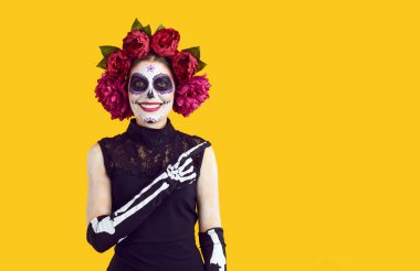 Kafatası şekeri makyajlı genç bir kadının portresi parmağıyla sağa sola bakıyor. Kırmızı şakayıklardan yapılmış çelenk, siyah elbise ve işaret parmağıyla işaret eden iskelet eldivenler giyen genç bir kadın.
