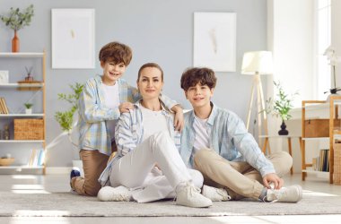 Oturma odasında yerde iki oğlu olan güzel bir annenin portresi, yakın plan. Tek başına çocuk yetiştirme kavramı. Genç oğlanlar, genç annelerinin yanında. Mutlu çocukluk