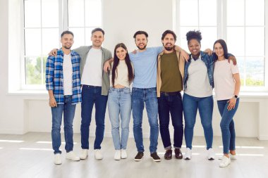 İçeride sarılan bir grup gencin portresi. Arkadaşlık kavramı, bağlılık ve takım ruhu duygusu, destek. Çok kültürlü meslektaşlar arasında sıcaklık ve neşe