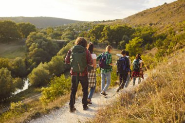 Dağlarda yürüyüş yaparak birlikte tatilin tadını çıkaran bir turist takımının arka planda görüntüsü. Grup bir gezide, boş zamanlarının çoğunu doğa keşfi yaparak ve yürüyüş yaparak geçiriyor..