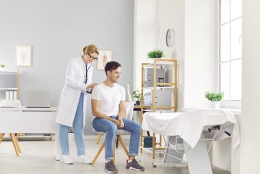 Steteskoplu doktor kalbi, akciğerleri, erkek sağlık hizmetlerini, kadın doktor muayenesini dinliyor. Erkek hasta sağlık hizmetleri profesyonel sağlık kontrolü için hastanede.