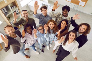 Mutlu gülümseyen, neşeli iş adamlarının kamera karşısında oylama yapan üst düzey bir portresi. Şirket çalışanlarından oluşan bir ekip toplantı sırasında bir soruya cevap vermek için el kaldırıyor..