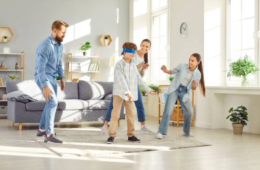 Large joyful family plays blindfolded games in living room. Children and parents participate in timeless games of blind mans buff game bringing light energy to family gathering Blind Mans buff game clipart