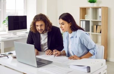 Konsantre olmuş iki ciddi iş adamı ve şirket çalışanı iş yerindeki mali belgelerle masada oturmuş bilgisayar monitörüne bakıyor. Muhasebeci iş konsepti.
