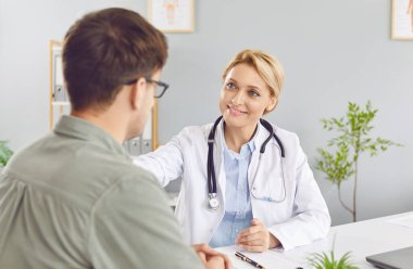 Doktor ya da hemşire klinikteki bir hastaya tıbbi danışmanlık ve destek sunar. Bu sağlık ziyareti, bir hastane ortamında mevcut olan profesyonel bakım ve yardımı vurgular..