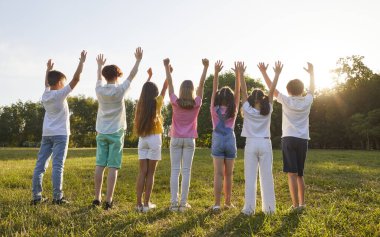 Bir grup çocuk sabahın köründe yeşil çimlerin üzerinde durmuş, gökyüzüne bakıyor ve ellerini güneşe kaldırıyorlardı. Doğa, yaz, çocukluk kavramı