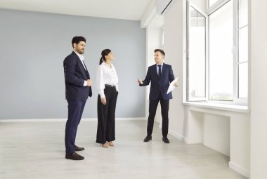 Bir emlakçı, bir erkek ve bir kadına yeni bir daire gösteriyor, yakın plan. Evli bir çift bir emlakçıdan ev kiralıyor. İşadamları bir komisyoncudan ofis satın alıyor, emlak kredisi alıyor.