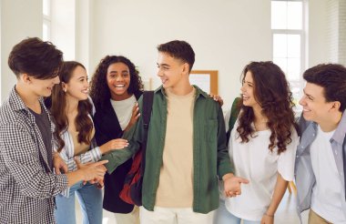 Bir grup mutlu genç öğrenci okul tatilinde sohbet edip sohbet ediyorlar. Sohbetleri ve gülüşleri, tatilde çocuklarla öğrenciler arasındaki haz ve dostluğu gösteriyor..